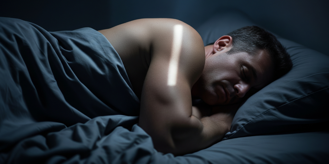 Muškarac spava dubokim snom u zamračenoj sobi, simbolizujući važnost sna za oporavak mišića.